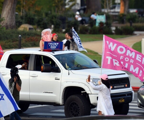 a trump car rally includes a woman holding a woman for trump flag