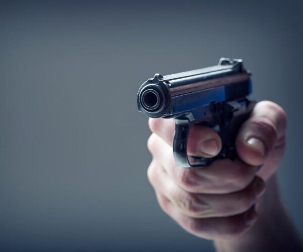 person's handing holding gun, pointing at camera