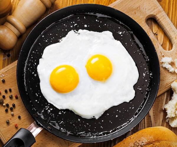 a pan on a cutting board with two fried eggs