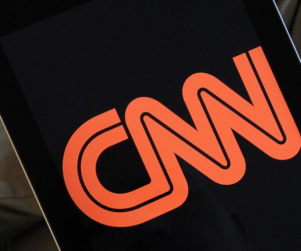 a man holds an ipad showing a cnn logo. 