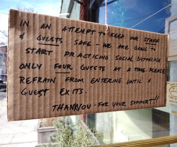 sign on a business tells customers to maintain social distancing