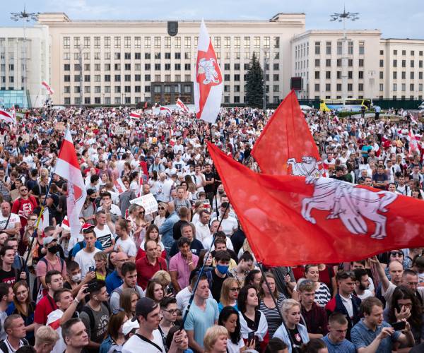 a massaive demonstration of people with a flag being waved