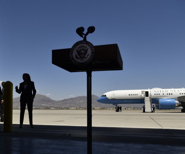 kamala harris standing far back from the lecturn before speaking with air force two in the background