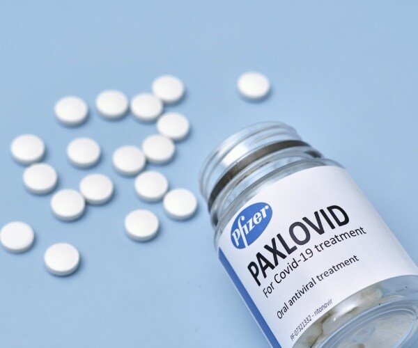 Paxlovid antiviral in container, with some pills spilled out on table