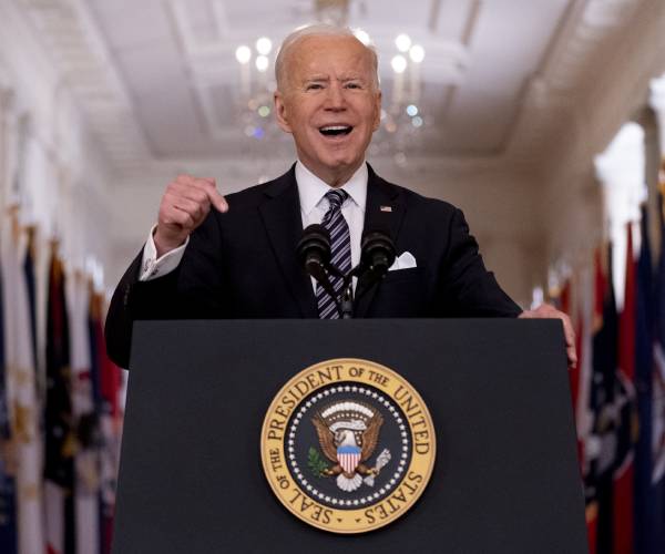 biden standing behind podium with presidential seal