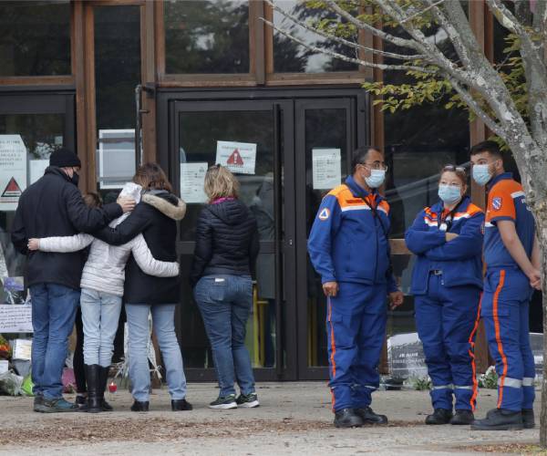 people stand outside the school and hug each other