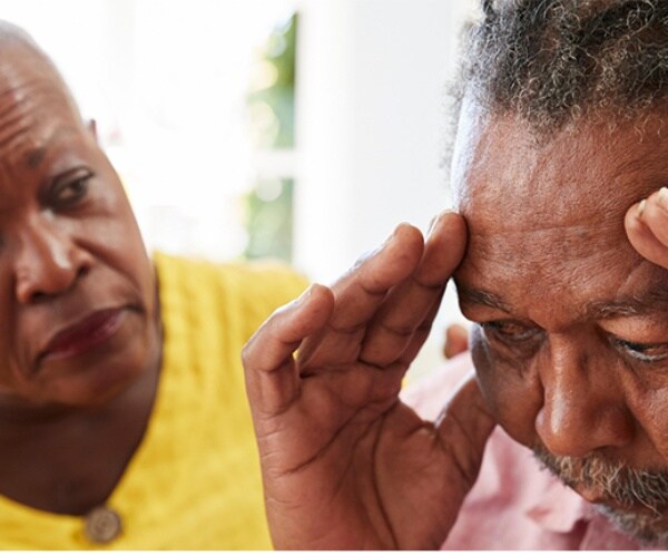 woman looking worriedly at man who is holding his head 
