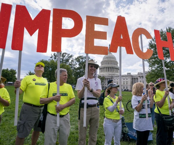 activists hold up signs spelling out "impeach" at the capitol in washington