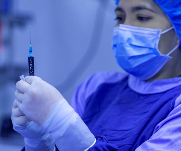 healthcare worker with syringe wearing surgical mask