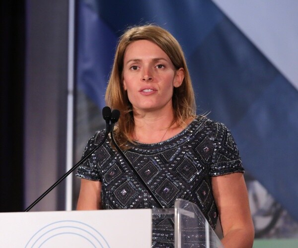 kennedy in a black sequined dress speaking at a podium