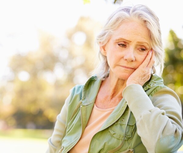 depressed older woman sitting on bench