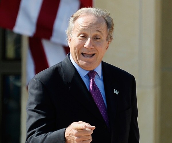 michael reagan delivers remarks to reporters with an american flag in the background