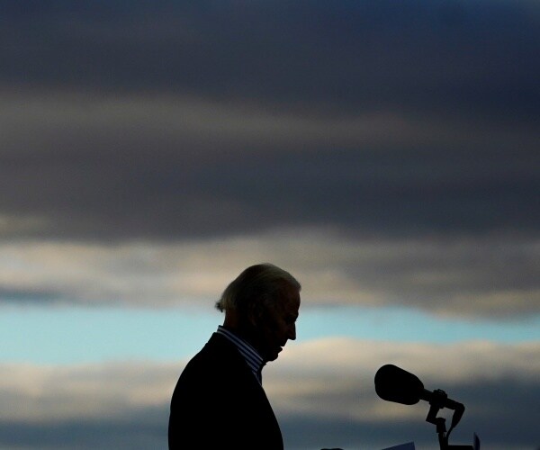 joe biden stands against a setting sun