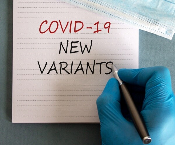 "COVID-19 NEW VARIANTS" written on pad by a gloved hand
