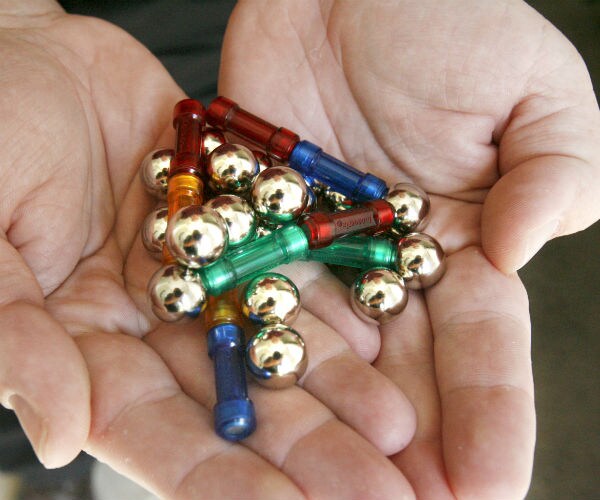 A man holds a handful of magnetic balls that many children have ingested.