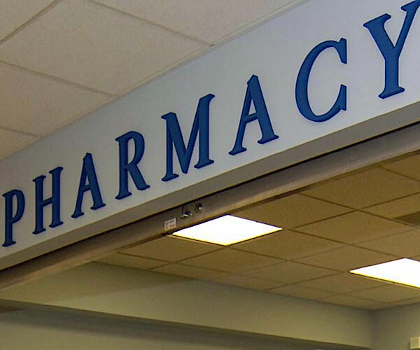 a sign for a pharmacy haves overheard the desk at a store