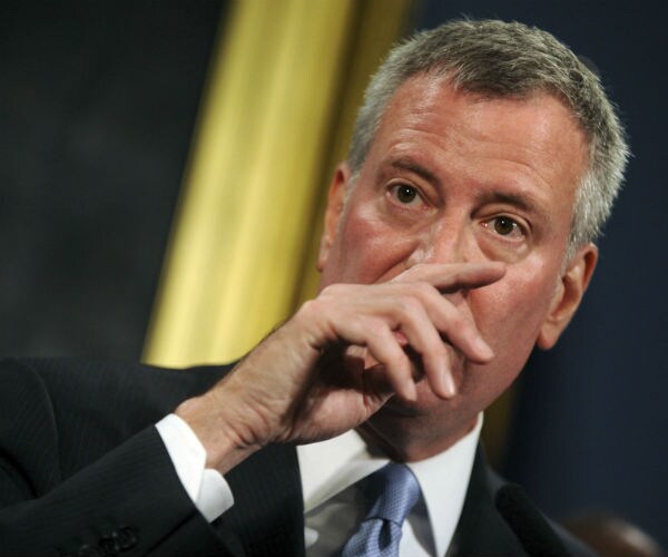 bill de blasio with his hand over his nose and mouth
