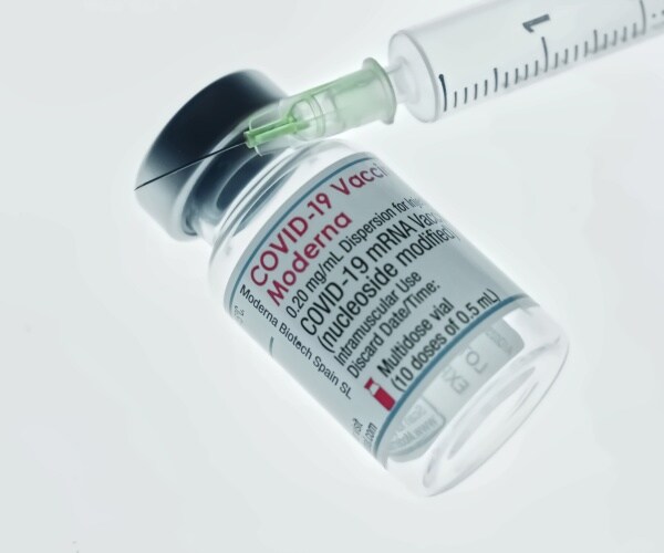 a vial labeled Moderna COVID-19 and syringe