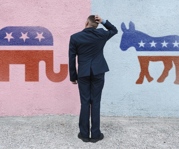 a man in a suit looks at republican and democratic logos and scratches his head