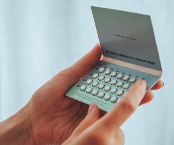 woman holds a pack of birth control pills