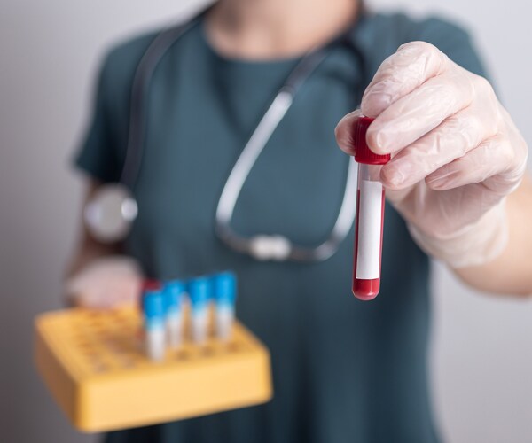 a healthcare worker holding up a vial of blood