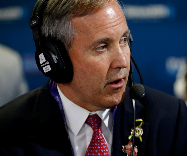 ken paxton in a suit and red and blue patterned tie wearing a headset
