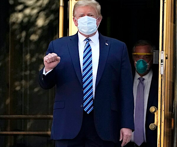president donald trump pumps his fist as he walks out of walter reed national military medical center