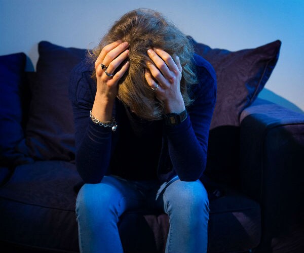 a persion sitting on a couch with their head in their hands
