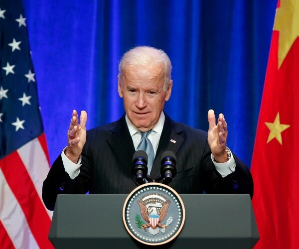 biden in a suit speaking next to us and chinese flags