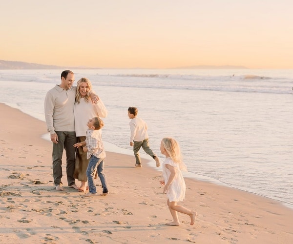 Mother and father playing on beach with three young children
