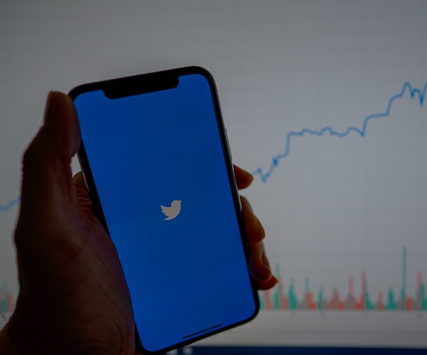 a man holds a smart phone with the twitter application logo opening up the application