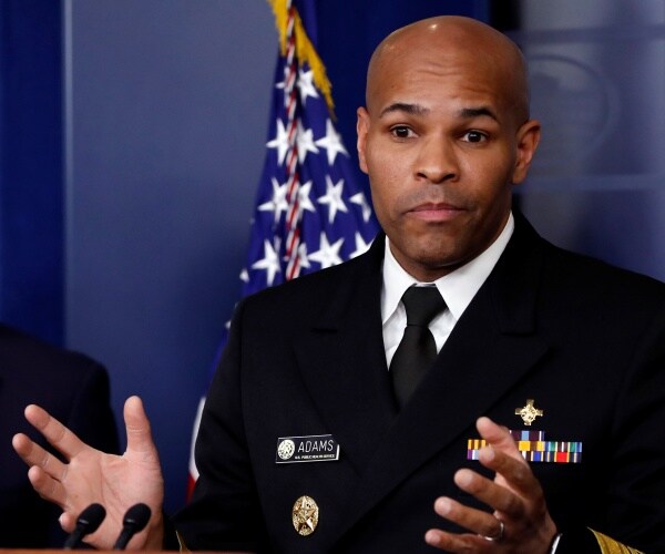 jerome adams in a suit with his hands raised while speaking at the coronavirus briefing