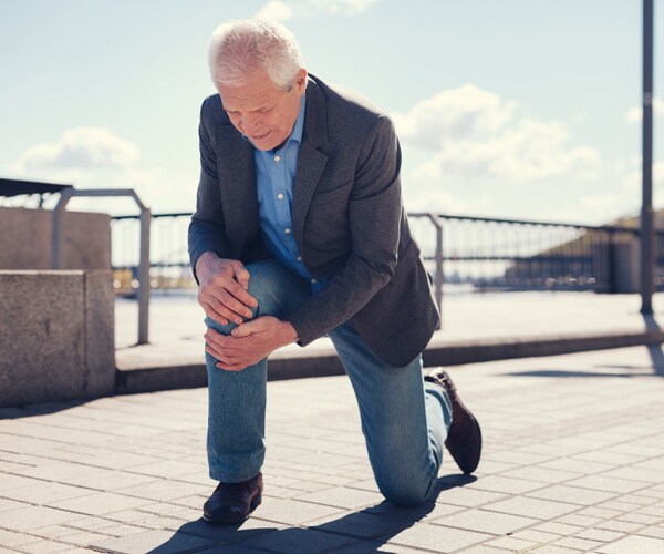 a senior man holds his knee after falling