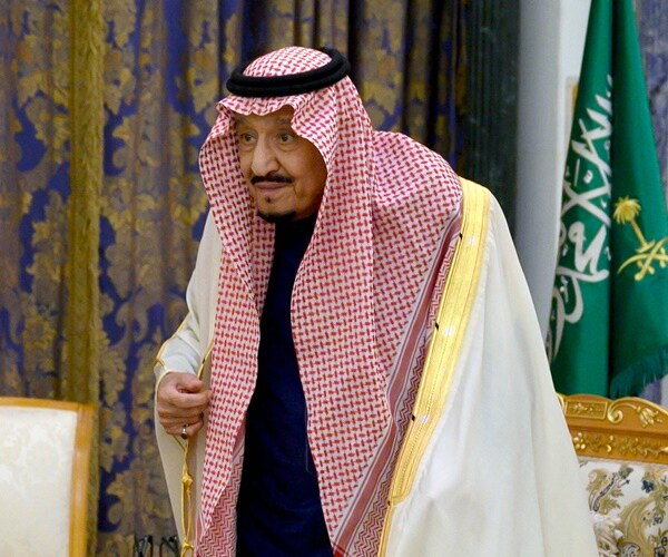 saudi king salman stands to greet someone