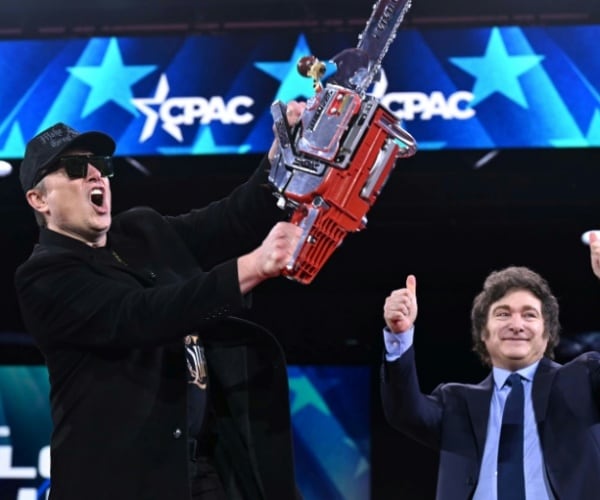Elon Musk holding a chainsaw on stage signifying all of the DOGE cuts