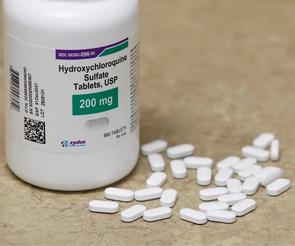 a bottle of hydroxychloroquine sits with tablets scattered