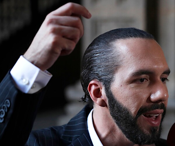 nayib bukele raises his right hand above his head during impassioned remarks into a mic