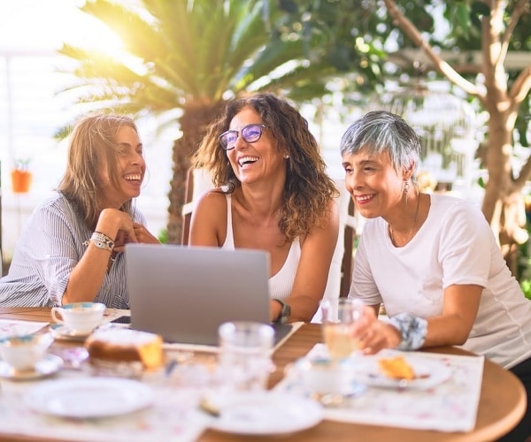 three middle aged women laughing together
