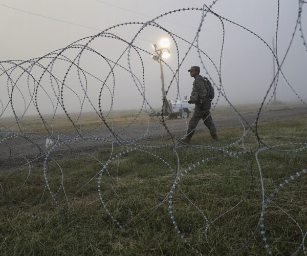 a soldier patrols at the u.s. border next to razor wire.