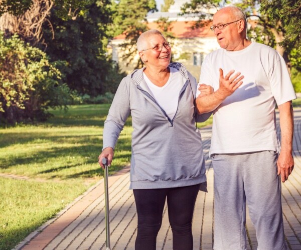 older couple walking slowly in park, smiling