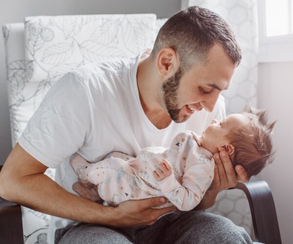 young dad holding newborn, looking closely at each other