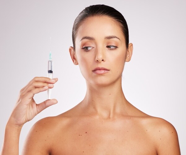 woman looking warily at a syringe 