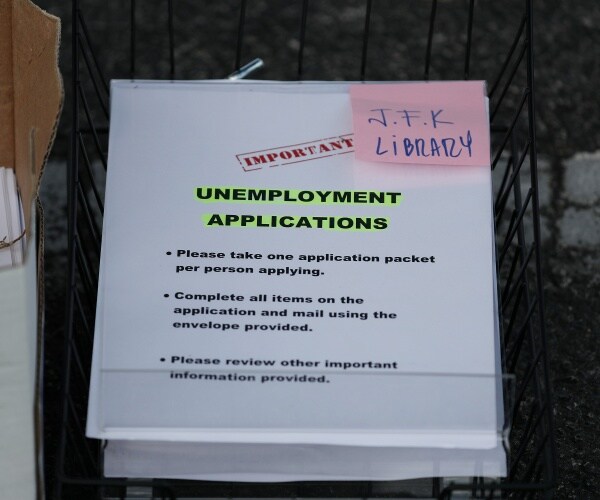 stack of unemployment applications with a pink post it note saying jfk library