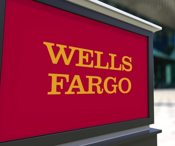street signage board with wells fargo logo. blurred office center and walking people background