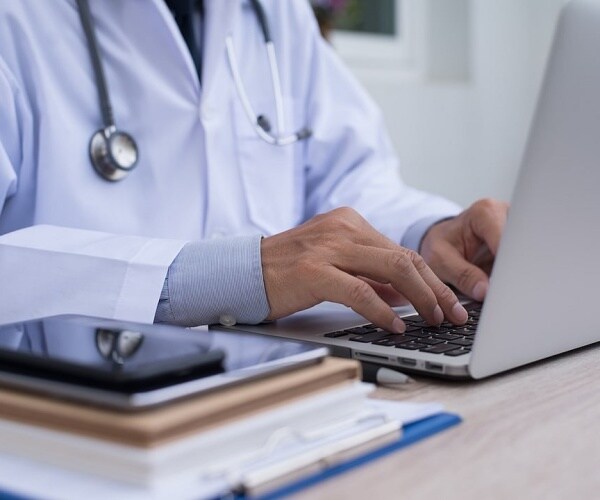 doctor typing a message on laptop to patient