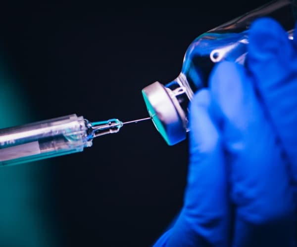 close-up of syringe in vaccine vial
