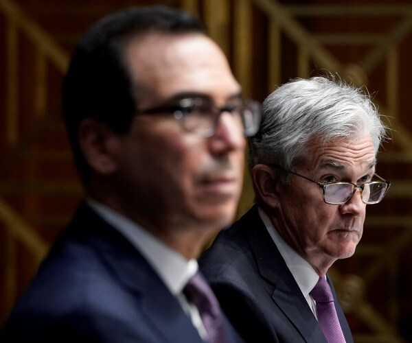 powell in a purple tie sitting next to mnuchin