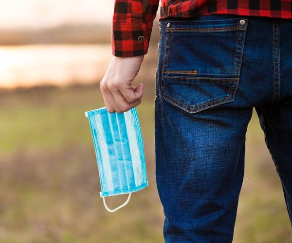 man holds medical mask in hand on street