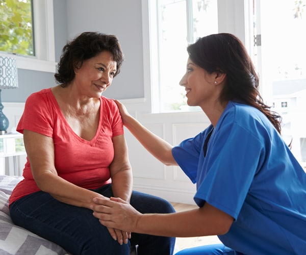 a visiting nurse reassuring a patient at home