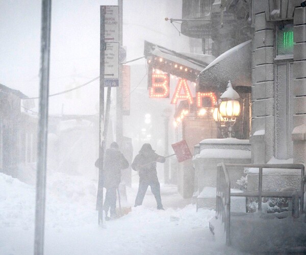 Workers shovel snow from their restaurant and bar entrance in midtown, New York City during a snowstorm Monday
